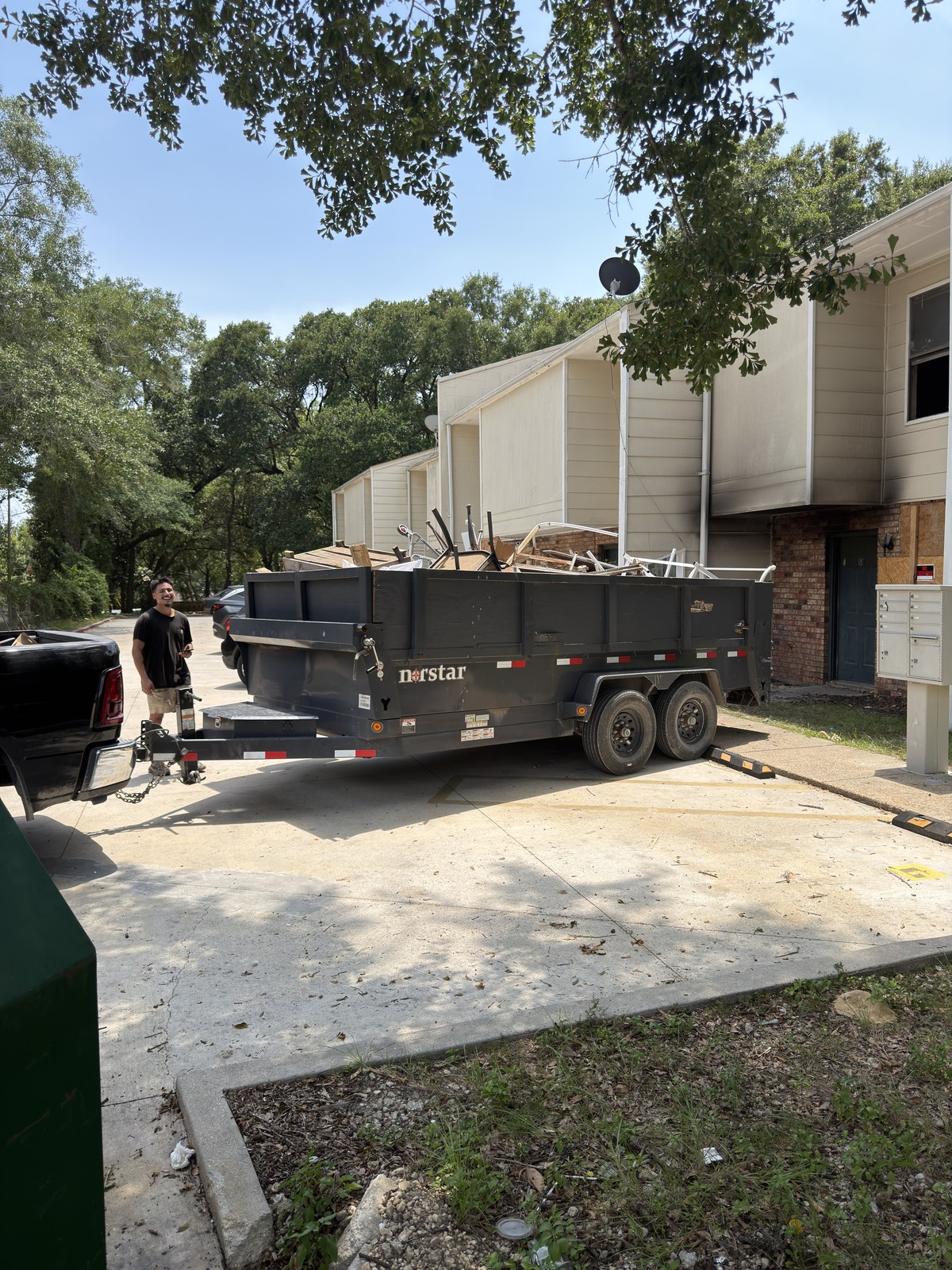 Black 18-yard dump trailer loaded with household debris during a Gulf Coast property cleanout