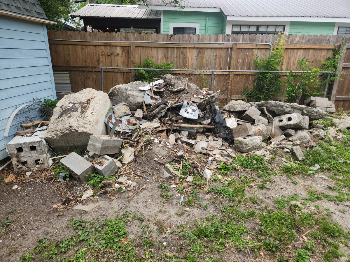 Concrete, block, and mixed debris awaiting removal beside a Gulf Coast home