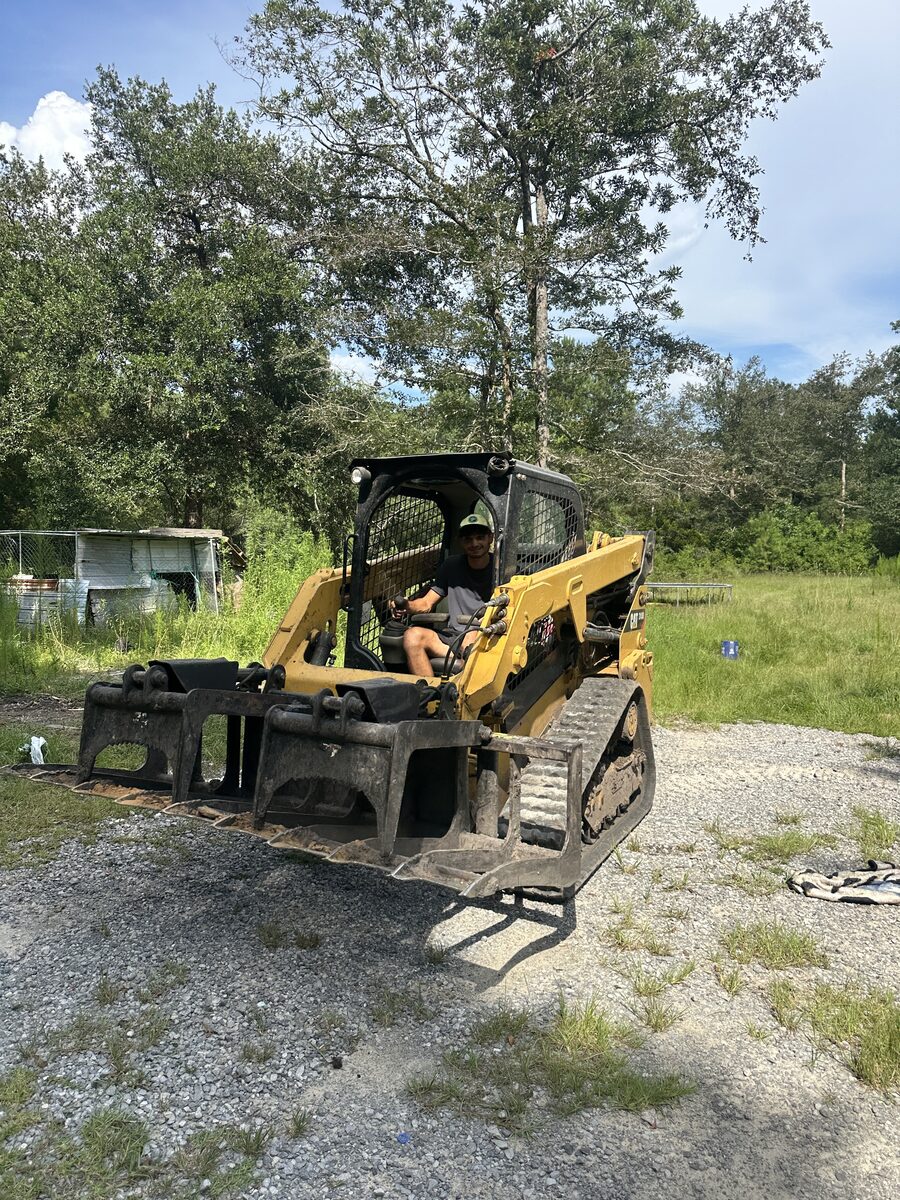 Marucci Enterprises operator seated in a tracked skid-steer with jobsite attachments
